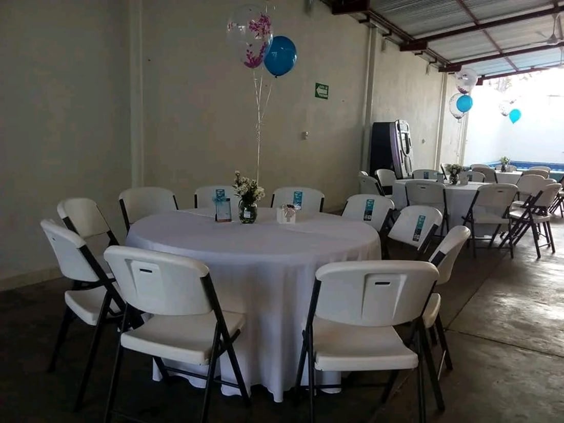 Mesa redonda montada con sillas plegables blancas de renta